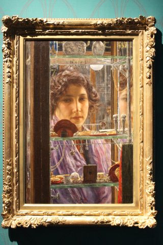 Dipinto “Seduzioni” di Vincenzo Migliaro che mostra una donna molto attratta dai gioielli presenti in vetrina. 